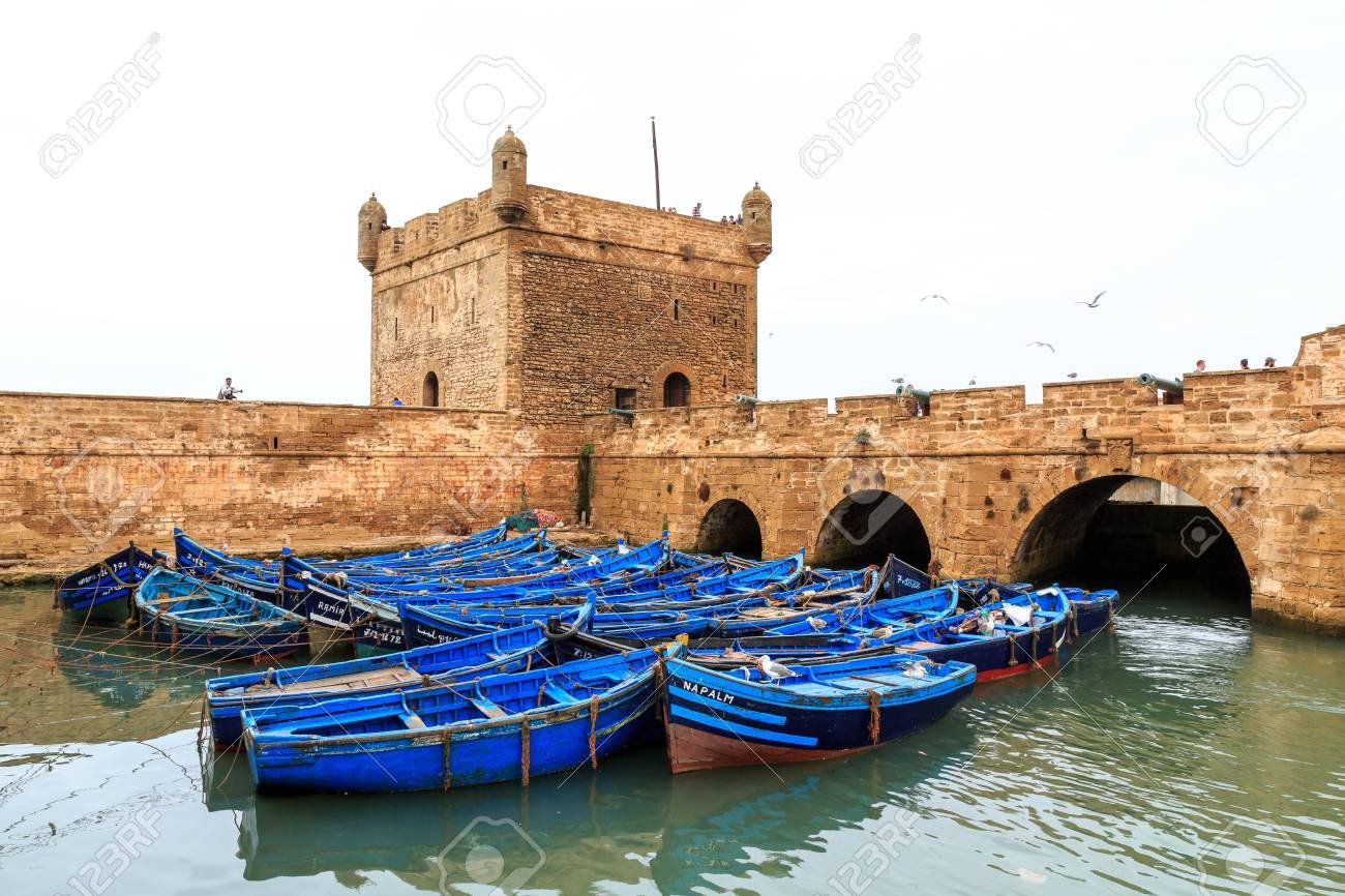 https://overlandtraveltips.com/wp-content/uploads/2026/08/74528831-small-blue-boats-in-the-harbor-of-essaouira-morocco-with-fortress.jpg